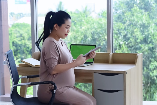 坐在窗边的孕妇，在办公室里工作，心情严肃，忙碌，图片下载