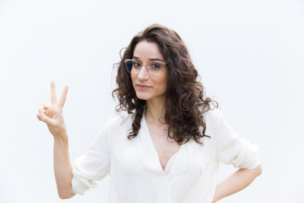 积极的女人戴着眼镜显示胜利的手势图片下载