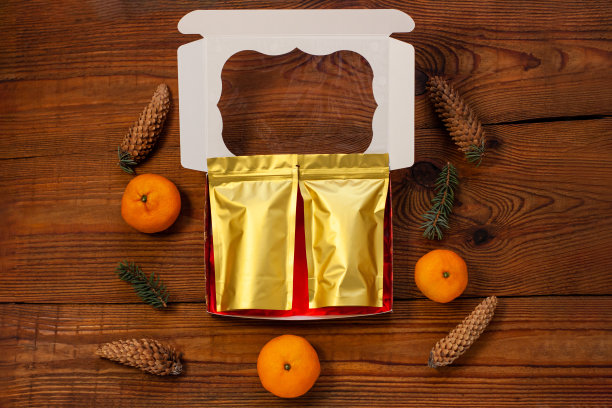 圣诞礼物装在金色的袋子里，红礼盒用新年装饰品包裹在质朴的木质背景上，平放图片下载