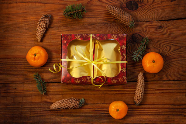 圣诞礼物装在金色的袋子里，红礼盒用新年装饰品包裹在质朴的木质背景上，平放图片下载
