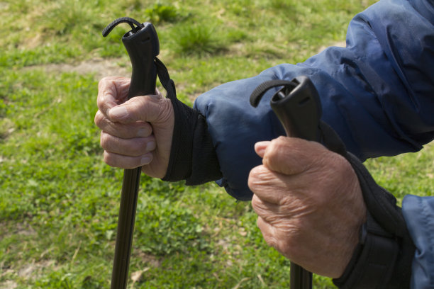 双手拄着拐杖，老妇人在清新的空气中积极地参与体育运动图片下载