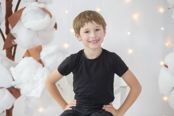 一个在明亮背景上穿着深色衣服的男孩。快乐的孩子微笑图片下载