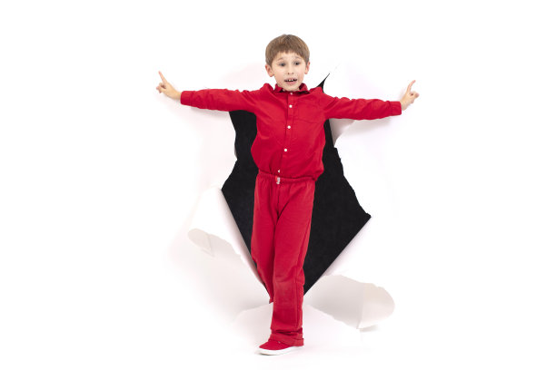 一个孩子从纸的洞里钻出来。男孩显示纸板。惊喜和新奇的概念图片下载