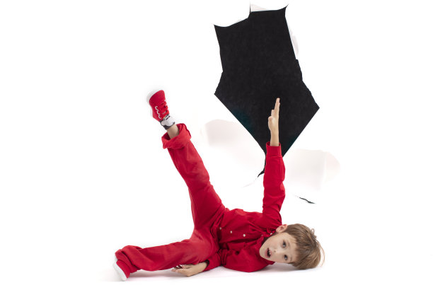 一个孩子从纸的洞里钻出来。男孩显示纸板。从广告牌上掉下来图片下载