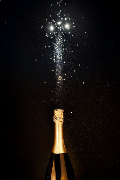 香槟瓶与金色飞溅，闪闪发光的黑色背景。平的。简约圣诞冬季派对概念图片下载