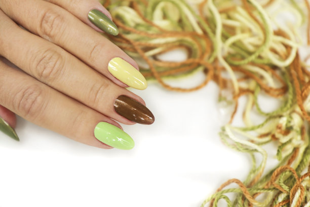 用彩色指甲油和珍珠指甲油涂在长椭圆形的指甲上。图片下载