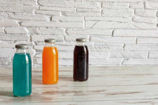 等张能量饮料。瓶装运动饮料与不同的口味和康普茶添加在木制背景。图片下载