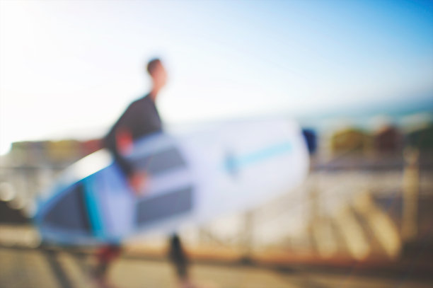 散焦站立划水板在木板路上走向大海图片下载