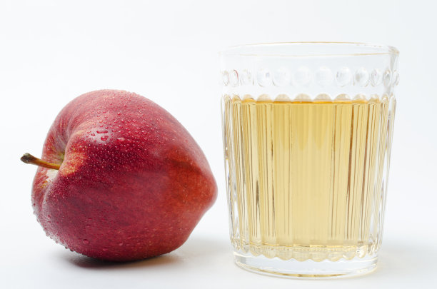 一个新鲜的红苹果与水滴和一杯甜可口的苹果汁在白色的背景图片下载