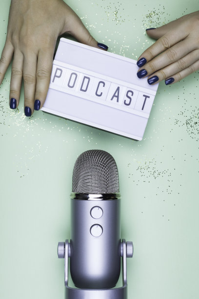 在灯箱和桌子上的专业麦克风上的女人手拿着标志播客。俯视图拍摄的播客工作室premier在薄荷背景图片下载