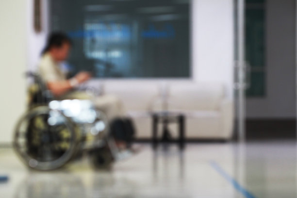 模糊的形象。背景模糊的一名男子坐在轮椅上在医院等待治疗。健康护理或家庭关系概念。图片下载
