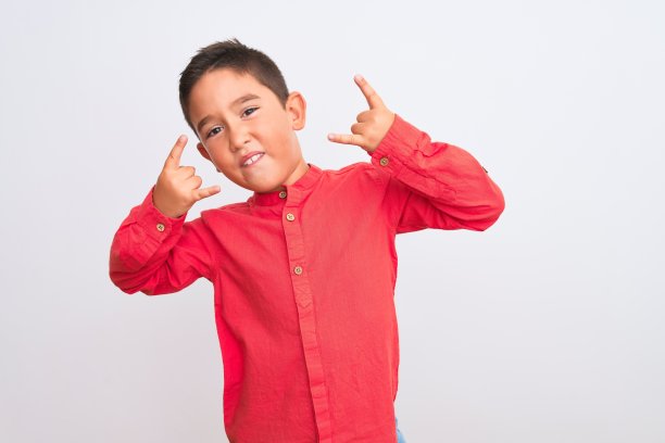 漂亮的男孩男孩穿着优雅的红色衬衫站在孤立的白色背景大喊与疯狂的表情做摇滚符号与手举起。音乐明星。沉重的概念。图片下载