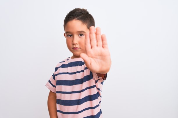漂亮的小男孩穿着休闲条纹t恤站在孤立的白色背景做停止用手唱歌。警告表情与否定和严肃的手势在脸上。图片下载