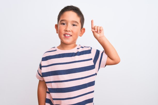 美丽的男孩男孩穿着休闲条纹t恤站在孤立的白色背景显示和指向第一个手指，同时自信和快乐的微笑。图片下载