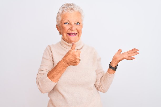 一位白发苍苍的老妇人穿着高领毛衣站在孤立的白色背景下，伸出手掌，竖起大拇指做着ok的手势，微笑着，开心而愉快图片下载