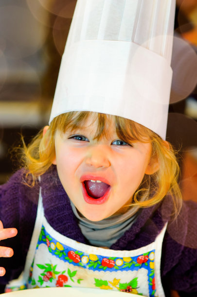 可爱的小女孩和她的厨师帽在厨房里图片下载