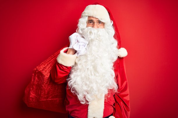 中年男子穿着圣诞老人的服装，拿着装有礼物的袋子，在孤立的红色背景下，聪明的脸上充满自信的表情，思考严肃图片下载