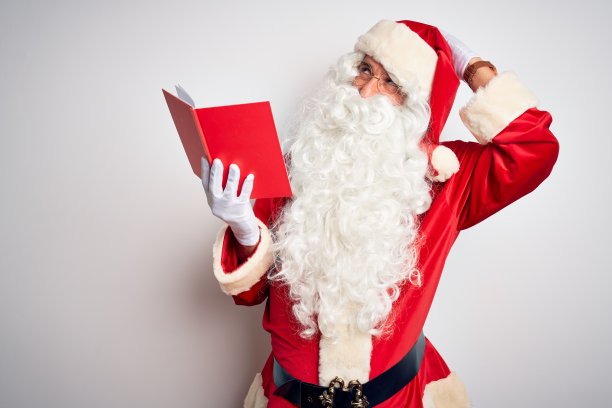 中年男子穿着圣诞老人服装，在孤立的白色背景下阅读，微笑自信地触摸头发，举起手的姿势，摆出迷人和时尚的姿势图片下载