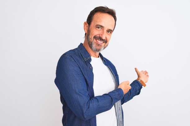 中年英俊男子穿着蓝色牛仔衬衫站在孤立的白色背景邀请进入自然微笑与张开的手图片下载