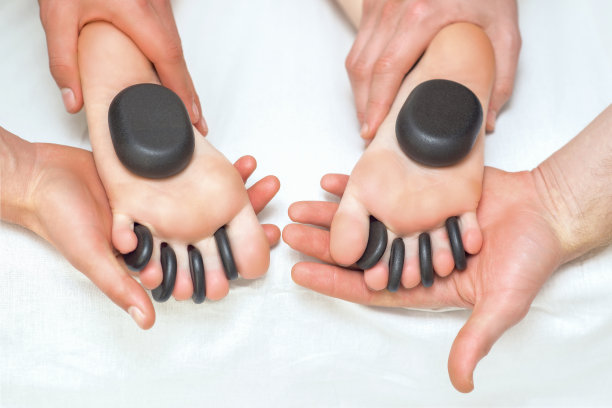 热按摩石头在女人的脚趾之间的脚。图片下载