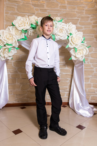 一个年轻男子的肖像在白色衬衫和黑色裤子的背景婚礼拱门图片下载