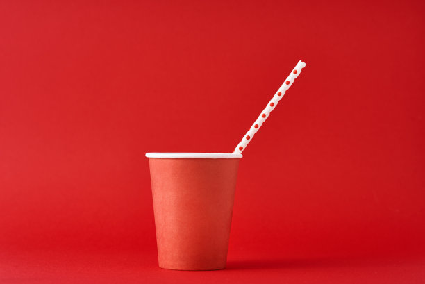 红色纸咖啡杯，红色背景上有稻草。极简主义风格图片下载