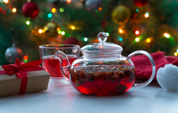 圣诞贺卡。白色桌子上的玻璃茶壶里装着水果茶。图片下载
