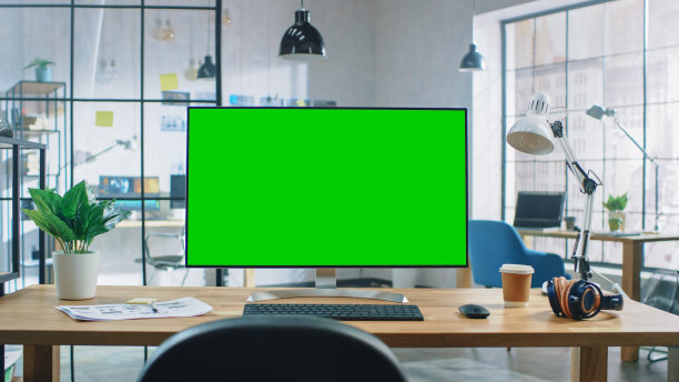 现代创意办公室的桌面电脑，宽大的绿色模拟屏幕。在明亮的创意阁楼背景为开发者和设计师专业工作。图片下载