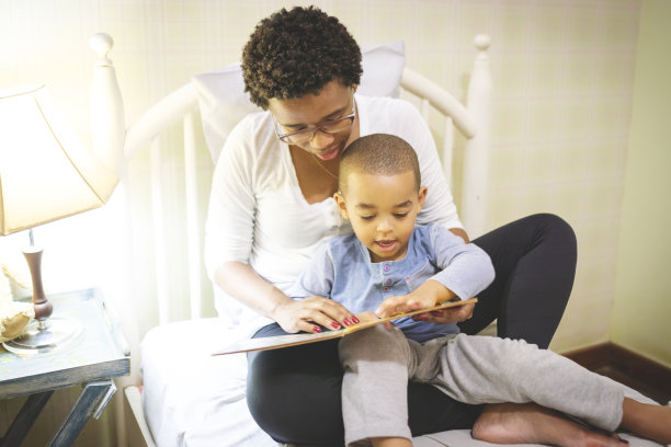 妈妈躺在床上给儿子读故事图片下载