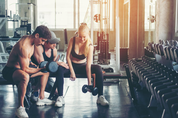 教练员与男女在健身房进行健身锻炼，以达到保健和瘦身的目的。健身教练和他的客户一起健身。饮食与健康运动的概念图片下载