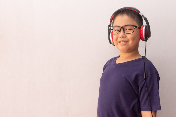 亚洲男孩戴着耳机听音乐。图片下载
