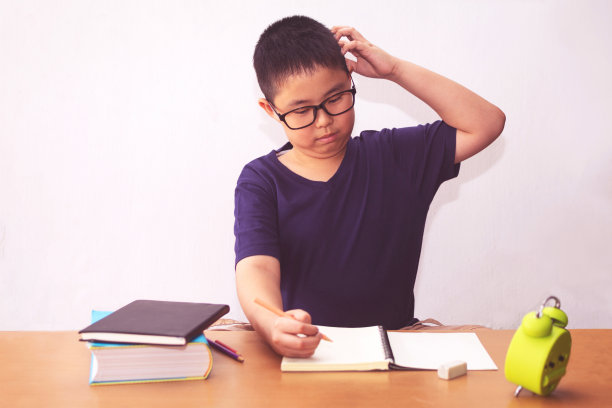 厌倦和疲倦的亚洲学生男孩做家庭作业图片下载