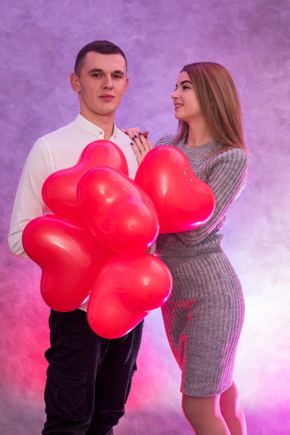 一对幸福的情侣在摆着心形的红色气球图片下载