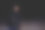 一个穿着皮夹克和黑色衣服的年轻女孩正走在一条废弃的沙路上，手里拿着一瓶威士忌。晚上在灯光下的汽车前灯和路灯图片下载