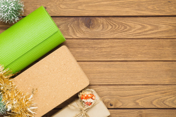 绿色瑜伽垫或普拉提垫、礼品盒和瑜伽砖，带有圣诞树装饰品，在木头上，用于圣诞快乐和新年快乐背景概念，带有复制空间图片下载