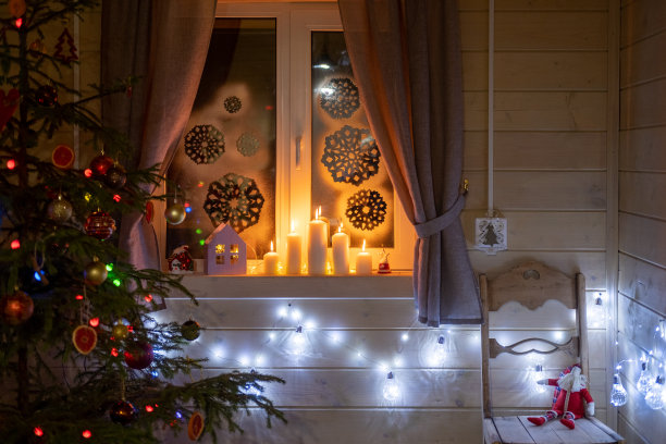 为圣诞节而装饰的木屋房间的内部。圣诞树上有玩具，窗台上有蜡烛，花环和老式椅子。圣诞节的概念图片下载
