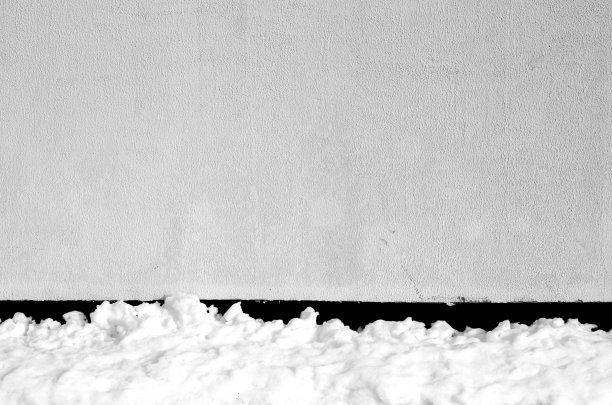 黑白色的堆在墙边的雪。图片下载