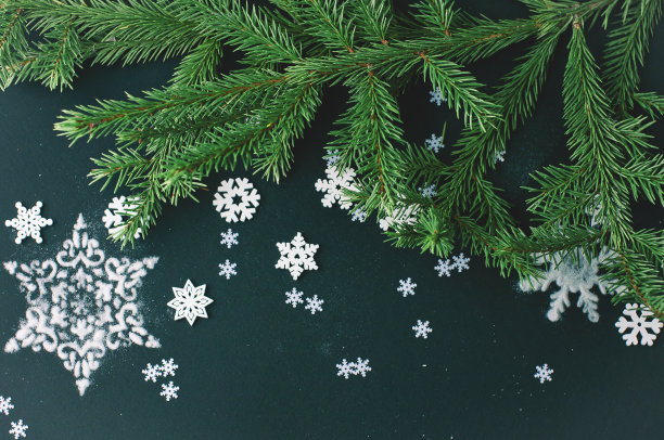 黑色的节日背景与白色和绿色的物体形成对比——天然的绿色云杉枝，白色的雪花，银色闪亮的圣诞玩具图片下载