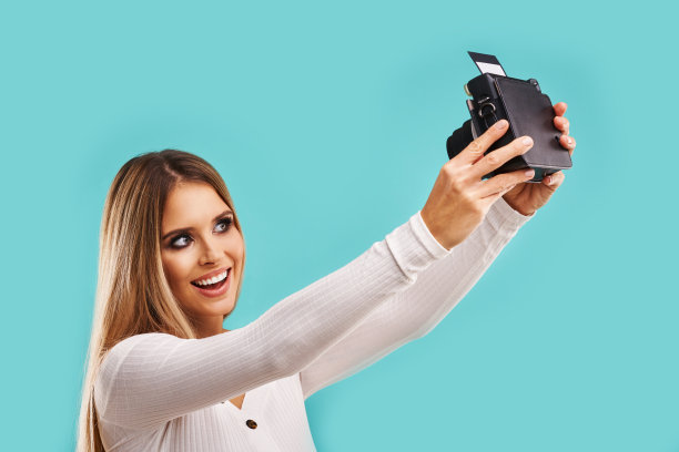 美丽的成年女人在蓝色的背景下拍摄即时照片图片下载