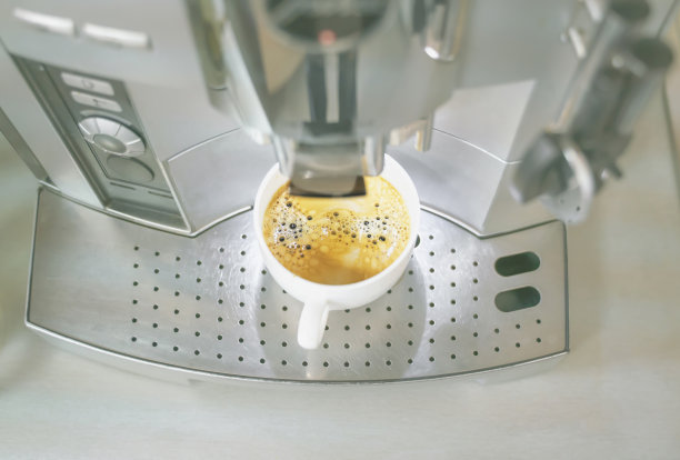 自动咖啡机分配一杯美味的热芳香咖啡到一个白色陶瓷杯图片下载