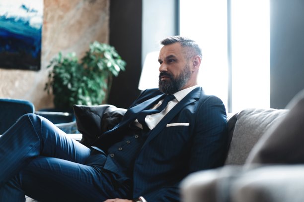 体贴帅气的商人坐在他的现代办公室里，坐在沙发上思考着商业理念图片下载