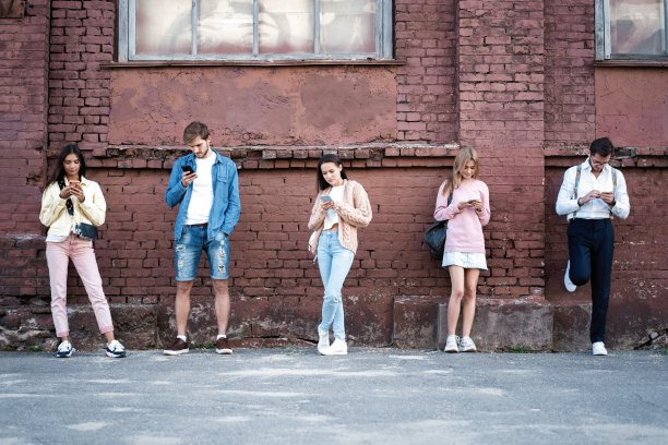 人们拿着智能手机站着，在社交网络上阅读信息和帖子。图片下载