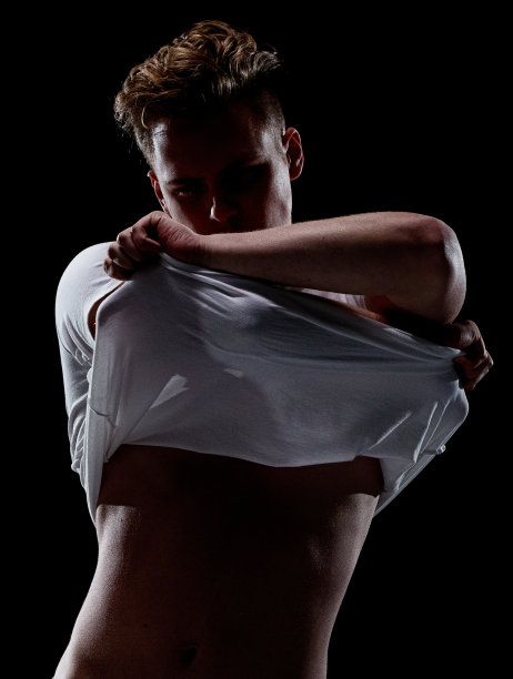 一个男人只有/一个人/腰部以上的20-29岁的成年英俊的人白人男性/年轻男子穿衣服/脱衣舞娘在黑色背景穿着t恤/衬衫谁是一个性感的象征/肌肉的建设谁是脱衣图片下载