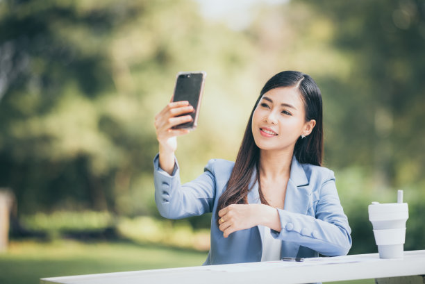 亚洲商业女性正在花园里用智能手机联系顾客。图片下载