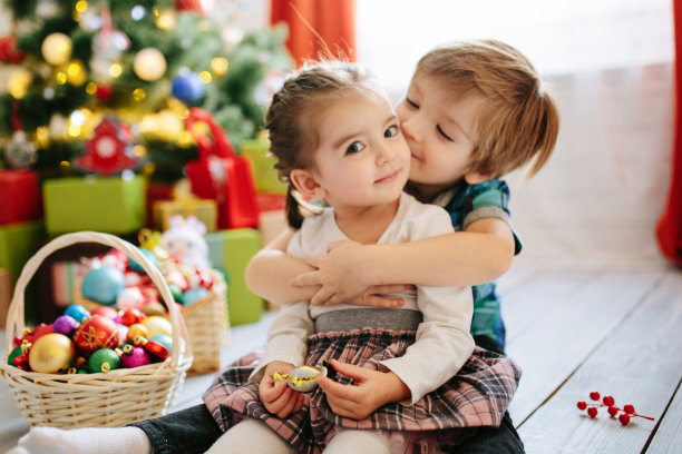 快乐的孩子女孩和男孩在一个圣诞节冬季阳光明媚的早晨，在一个装饰着圣诞树和礼物的圣诞庆祝室。图片下载
