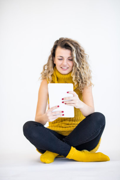 一名美丽的年轻女子在白色背景下使用数码平板电脑图片下载