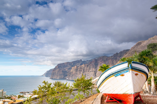 充满活力的水平景观与城市景观与陡峭的悬崖和阴天与在前景的船，Acantilados de Los Gigantes，波多黎各圣地亚哥，特内里费，加那利群岛，西班牙-库存照片图片下载