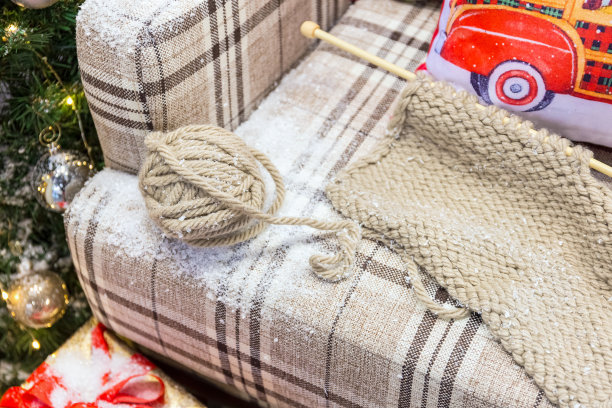 一套编织工具放在铺满雪的格子沙发上。图片下载