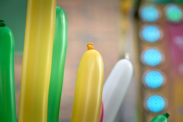 在游乐场和游乐园里有许多彩色的、细长的黄色、绿色和白色气球图片下载