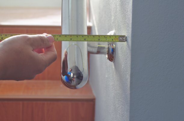 金属卷尺测量墙壁。安装栏杆。办公大楼的不锈钢扶手和白色楼梯图片下载